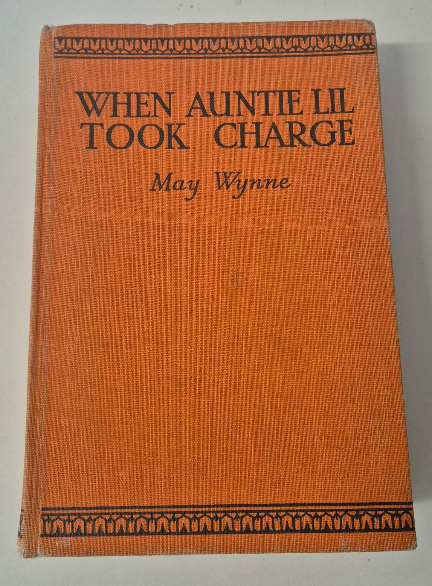 Book titled 'When Auntie Lil Took Charge' by May Wynne with an orange cover and decorative black text.